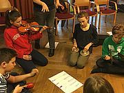 Foto von vier SchülerInnen, die mit Instrumenten rund um eine Notation am Boden sitzen